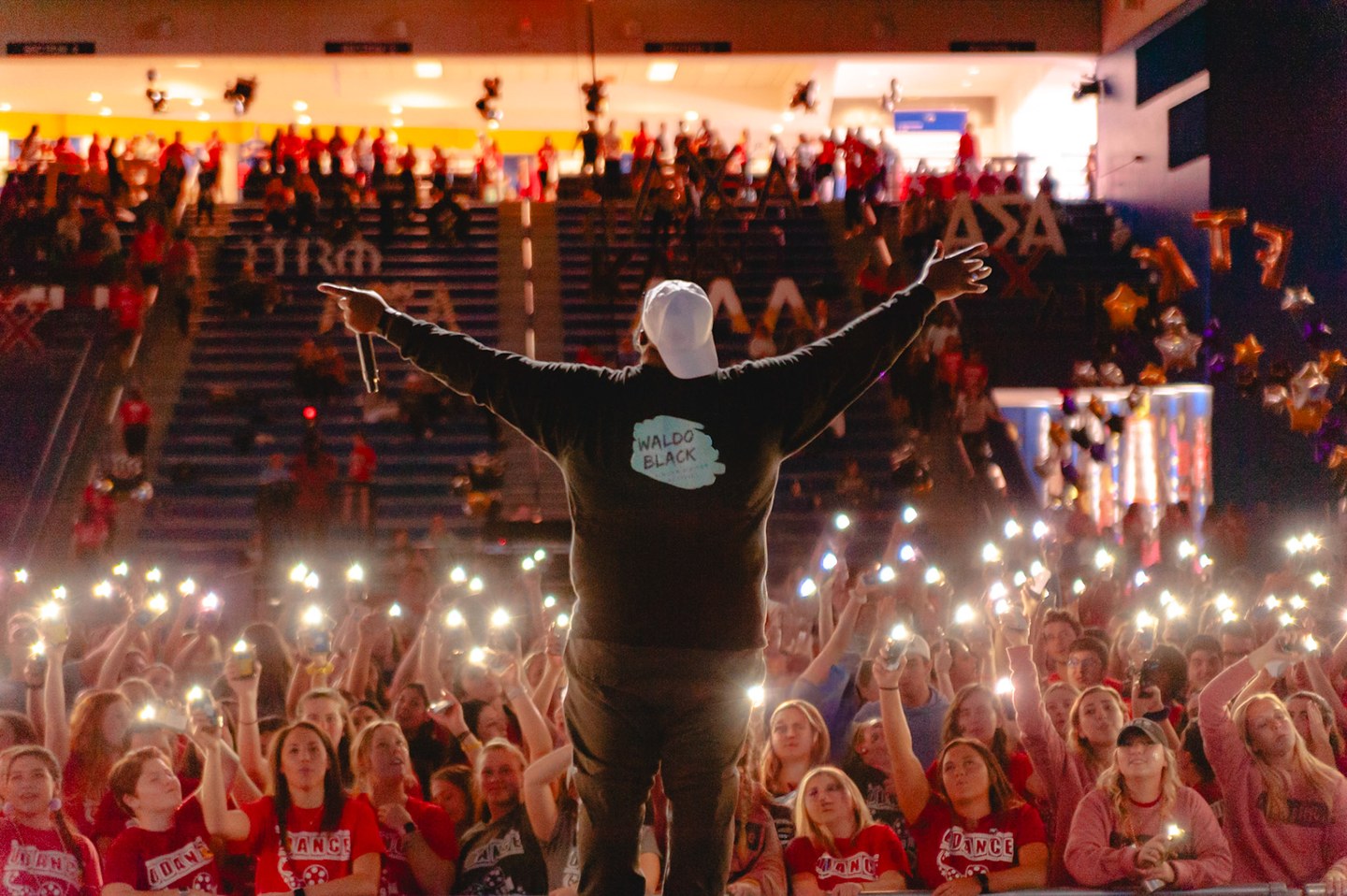 A performer facing a packed audience holding up illuminated phones