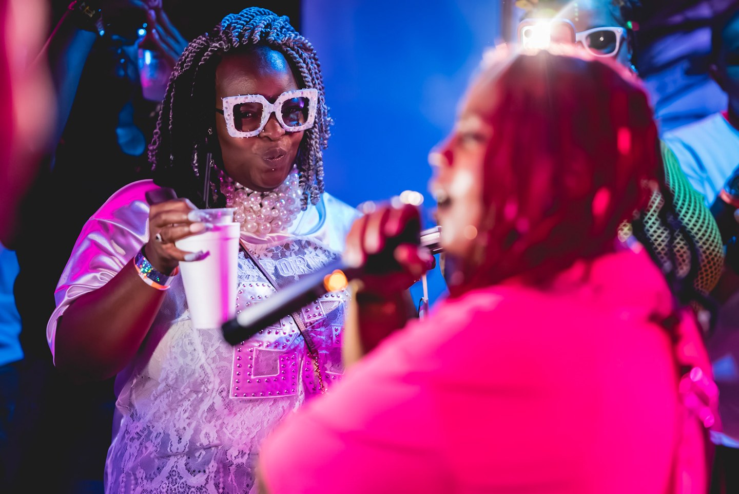 A vibrant close-up of two guests in sunglasses at a live music event